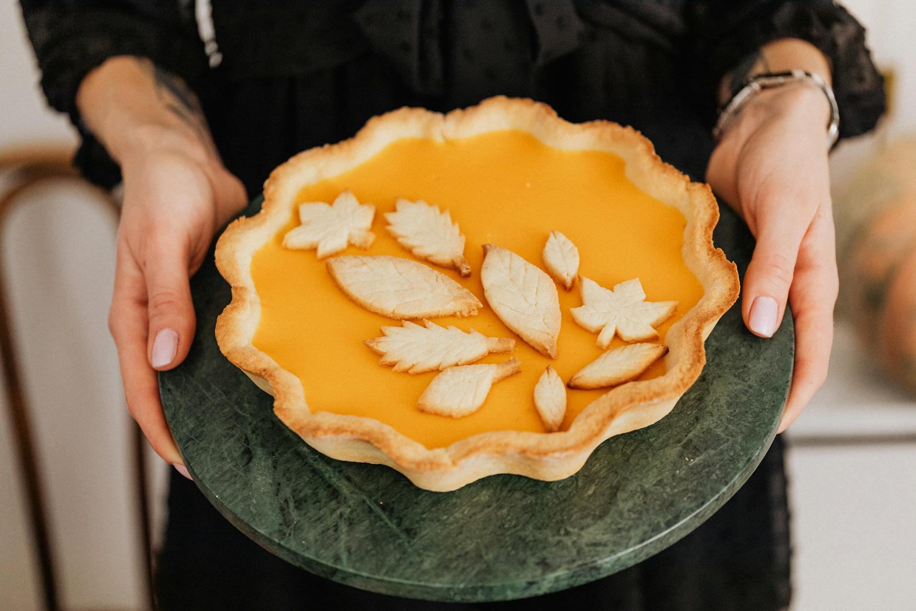 A delightful homemade pumpkin pie with decorative leaf shapes, perfect for autumn celebrations.
