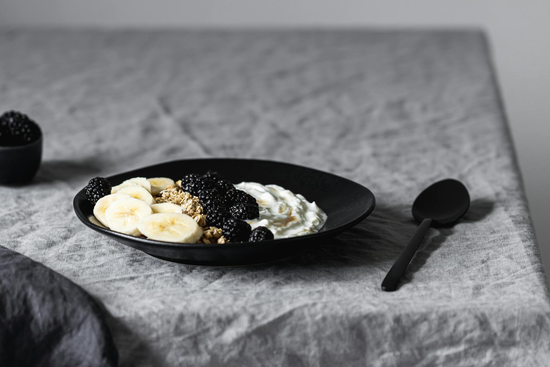 Delicious yogurt bowl with bananas, blackberries, and granola on a ceramic plate.