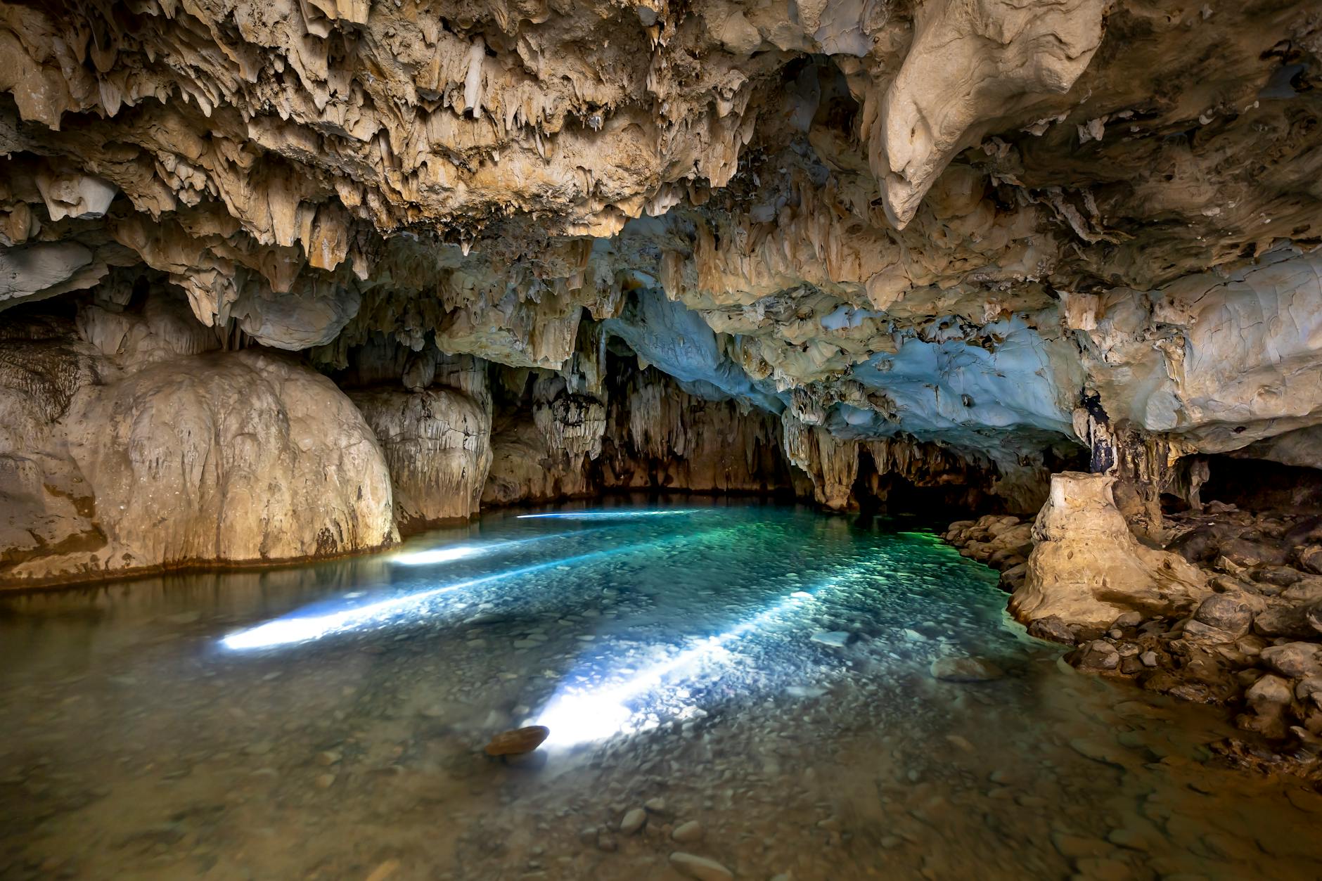 Breathtaking view of a naturally eroded cave with a tranquil lake illuminated by natural light.