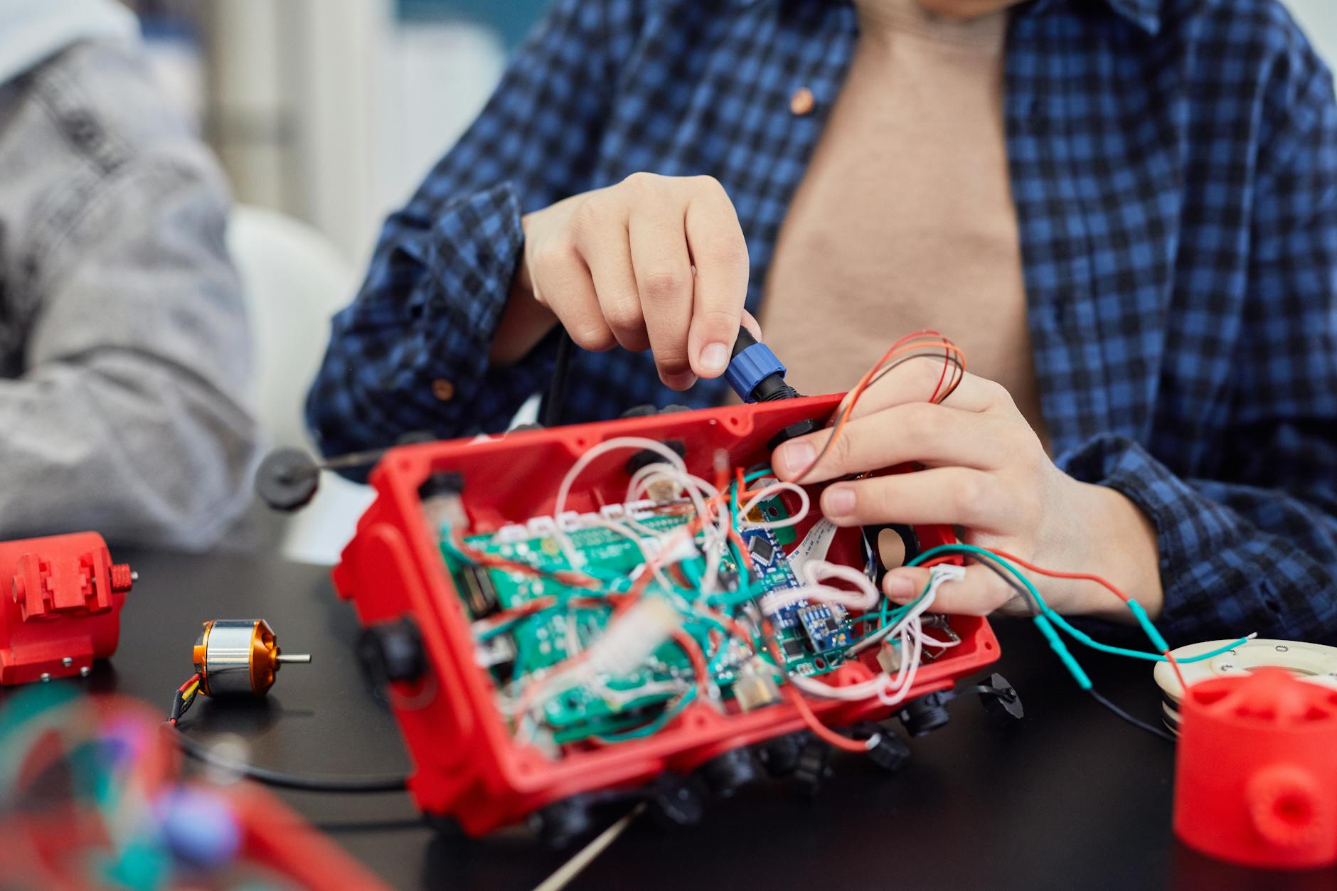 Close-up of hands assembling a robotic project with wires and circuits.