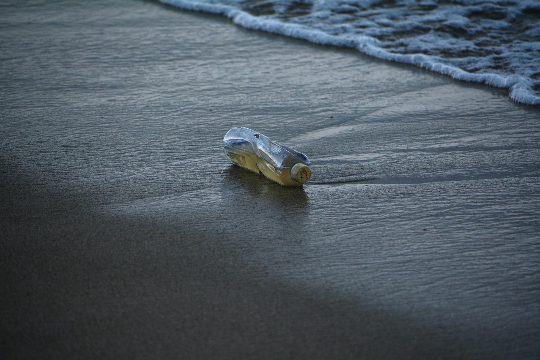 Plastic bottle littering a beach, highlighting pollution issues by the sea.