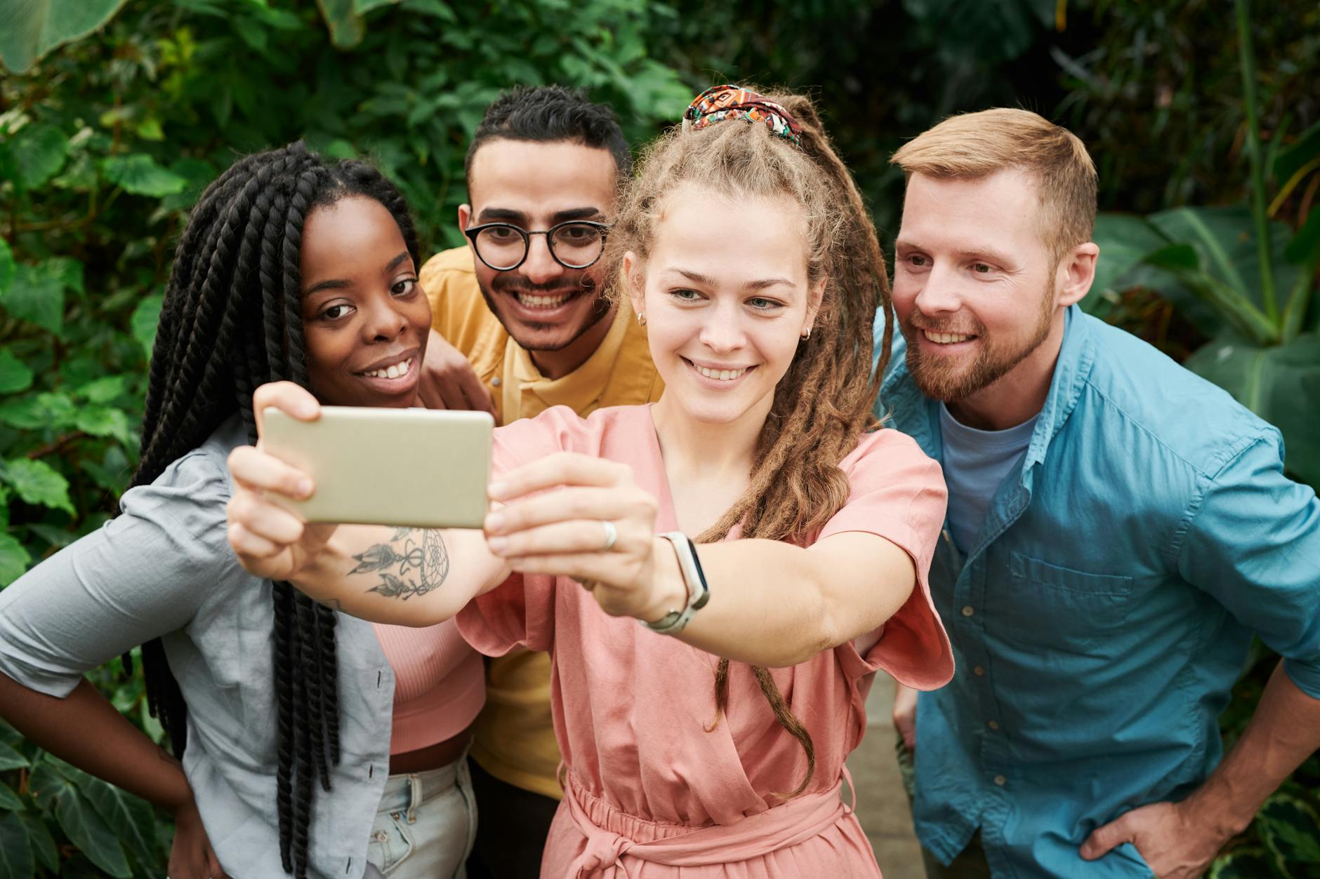 Diverse group of friends enjoying a fun outdoor photoshoot with a smartphone.