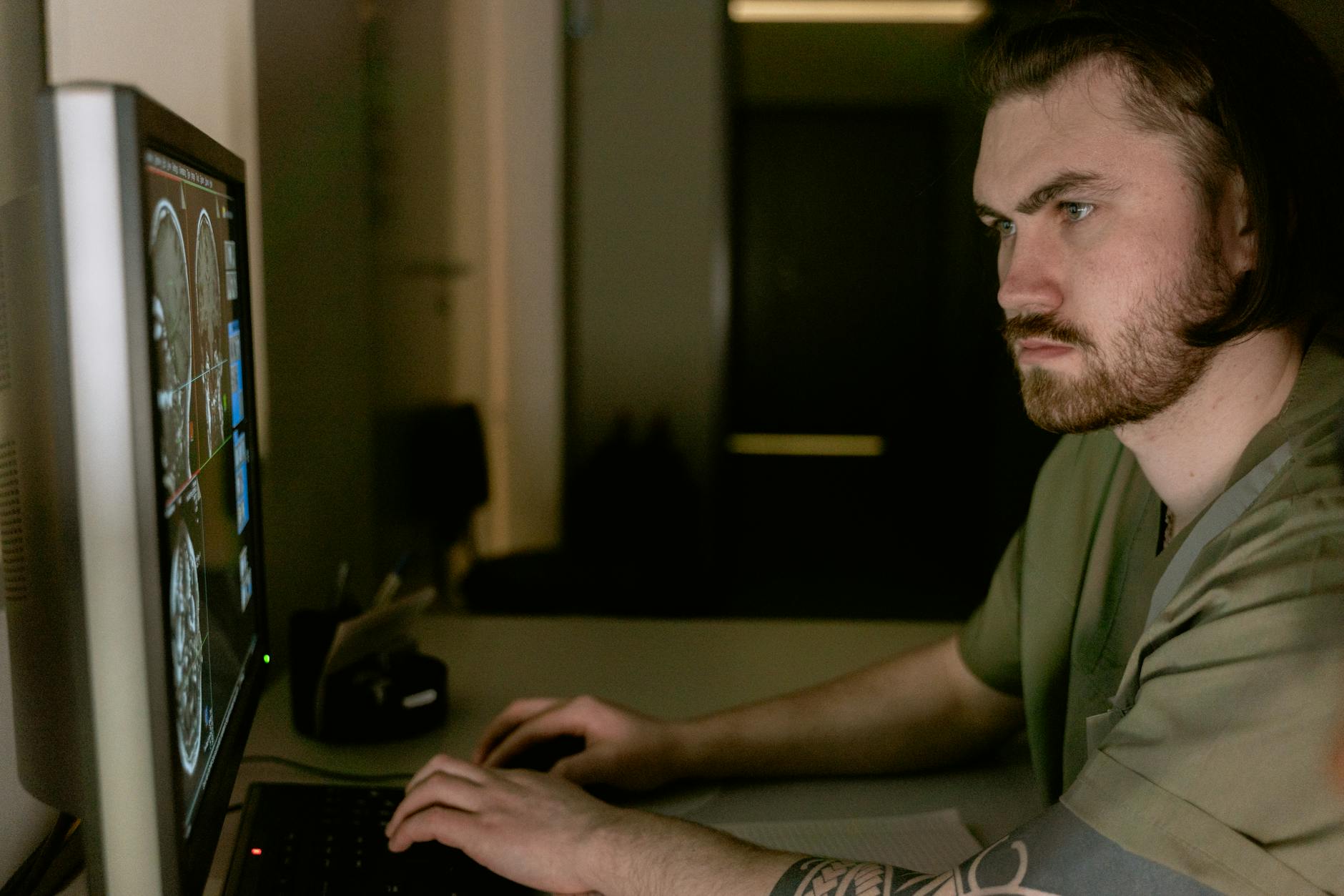 Radiologist intensely studies CT scan results on computer monitor in healthcare setting.