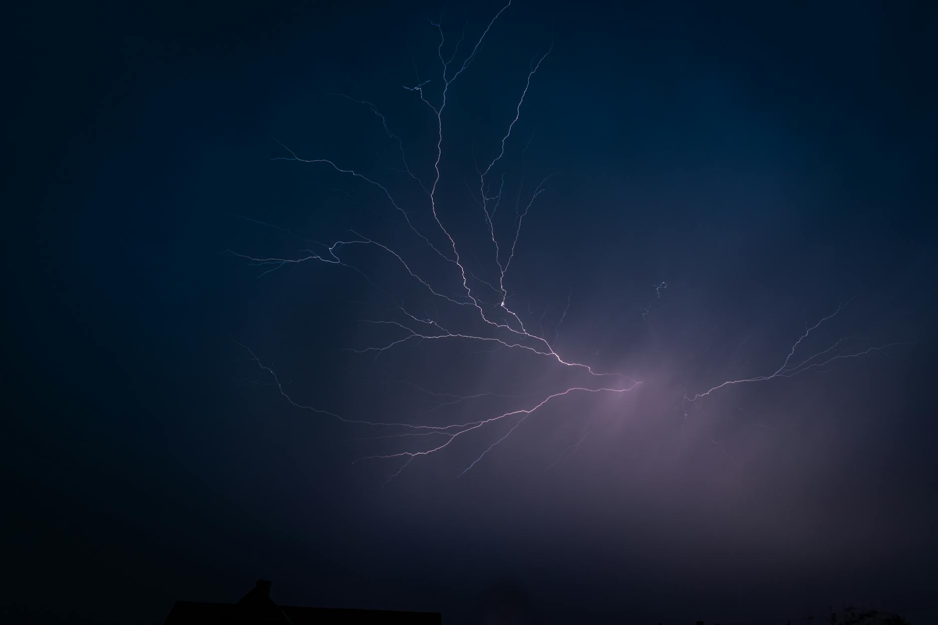 Capture of a powerful nighttime lightning strike illuminating a dark sky.