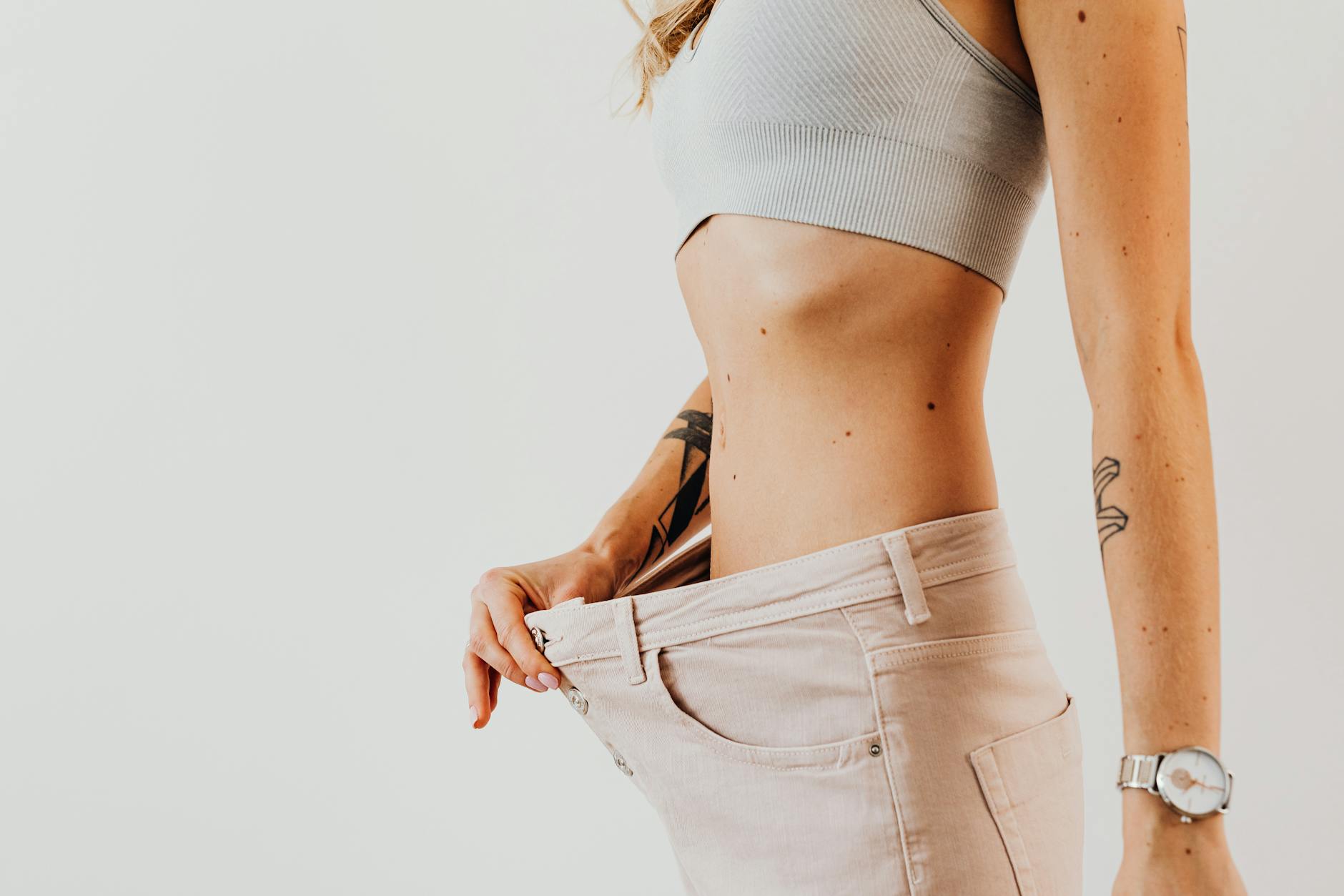 Close-up of a woman in oversized jeans symbolizing weight loss in a studio setting.