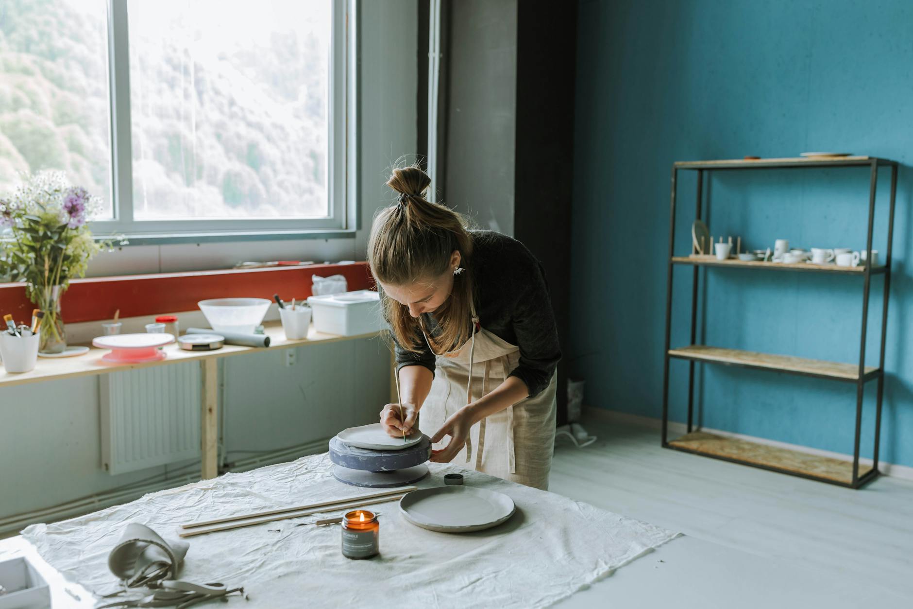 Craftswoman shaping clay in a vibrant studio with a cozy ambiance.