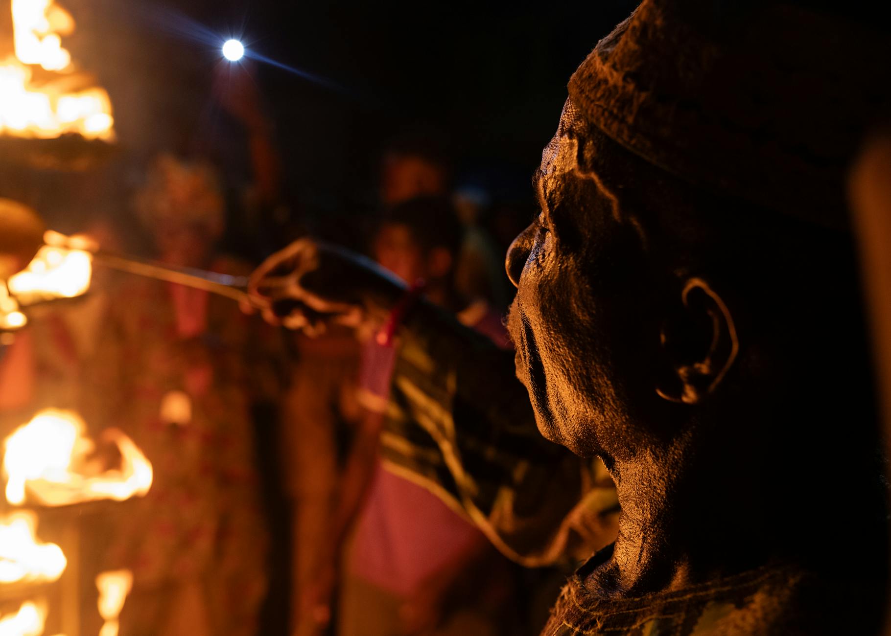 A captivating night portrait of a man performing a fire ceremony in Osun, Nigeria.