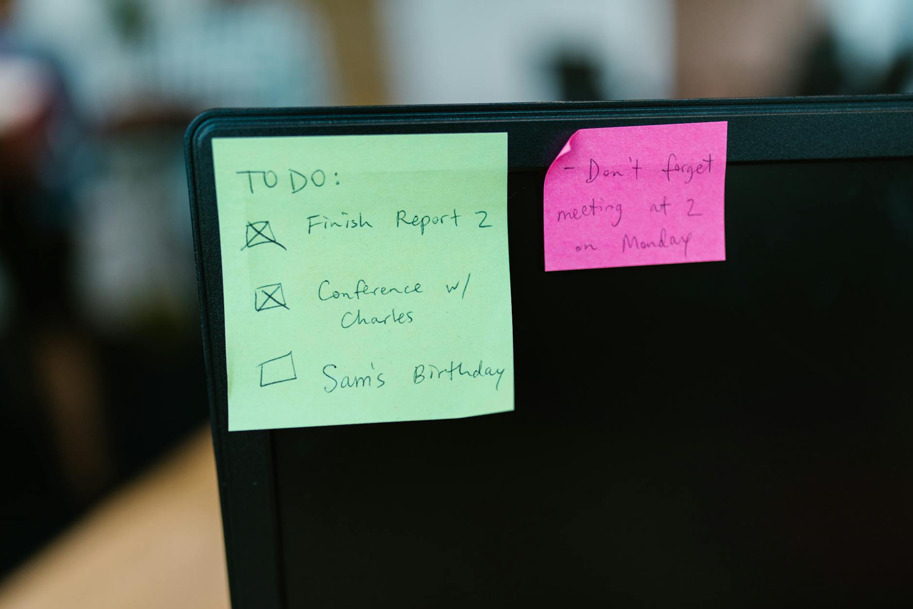Colorful sticky notes with reminders and to-do list on an office monitor.