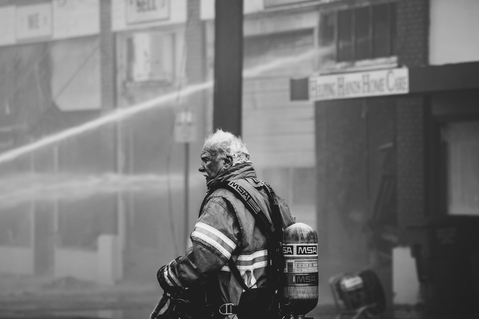 Heroic firefighter in protective gear managing a city fire, showcasing bravery and resilience.